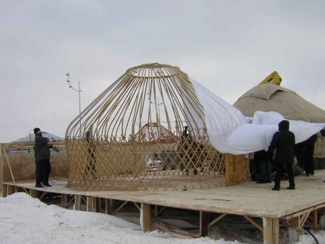 Step four: With the walls and roof frame in place, time to put on the walls. This yurt is a show yurt so the roof and wall covering is one piece, conveniently shaped.